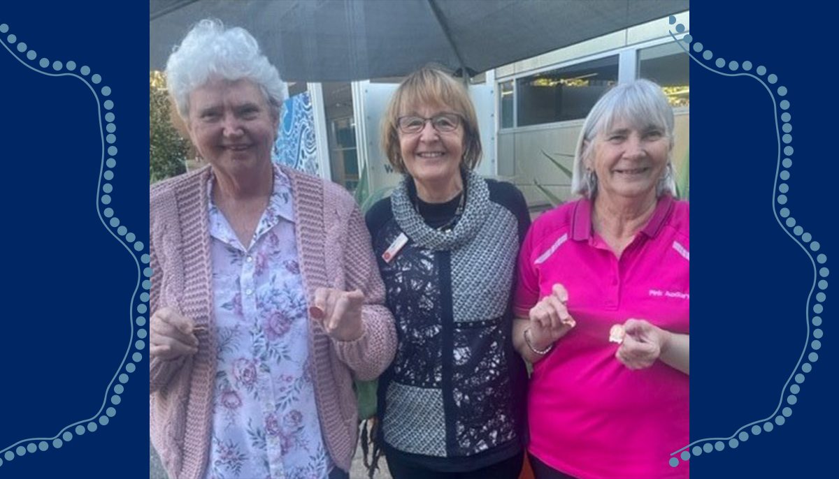 three women looking at the camera; the two on the outside holding service badges