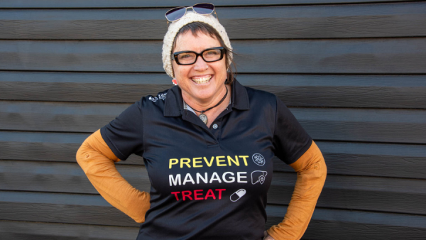 A woman wearing glasses and a shirt with Hepatitis C message of prevent, manage, treat.