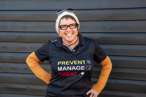 A woman wearing glasses and a shirt with Hepatitis C message of prevent, manage, treat.