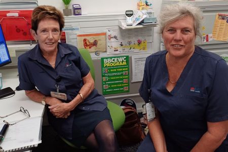 Two nurses seated, looking at the camera