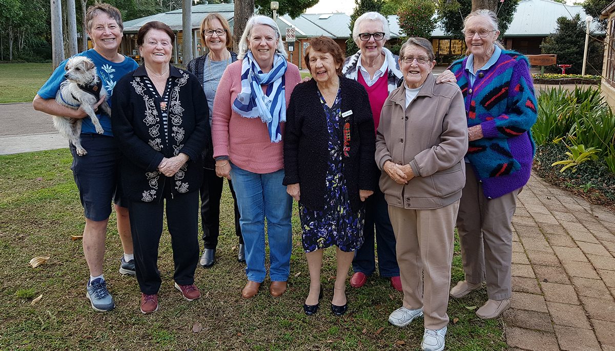 a group of older women standing together in a garden area