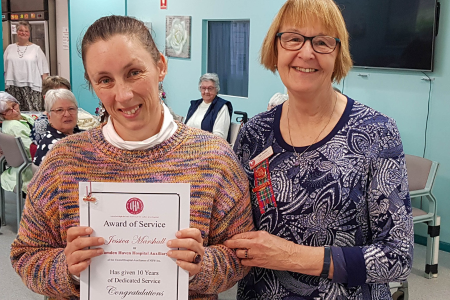 Two women, one with a certificate honouring her volunteer service.