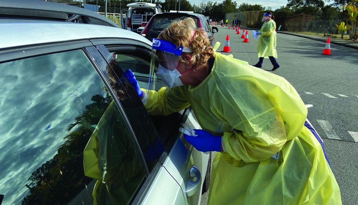 Nurse swabbing a person during drive-through testing