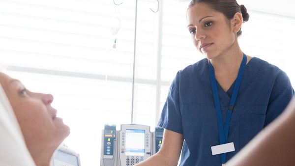 A female nurse looking at a patient lying on a bed