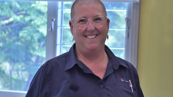 woman with a shaved head smiling broadly.