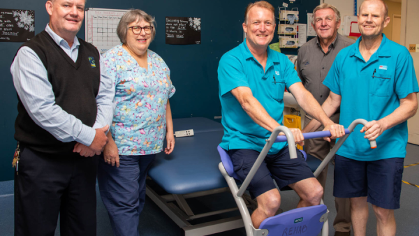 Five people in a rehabilitation unit with a new piece of equipment