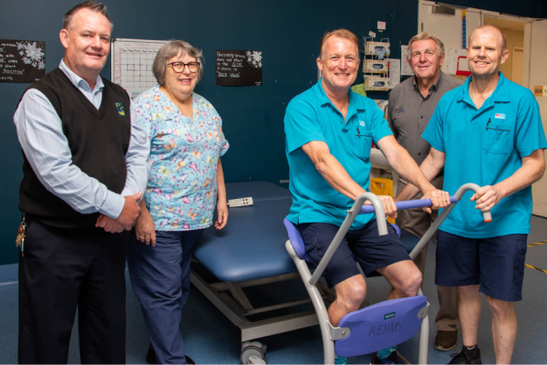 Five people in a rehabilitation unit with a new piece of equipment