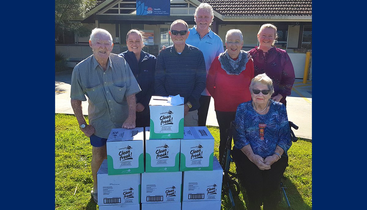 a group of people standing in front of a hospital and behind a pile of boxes.