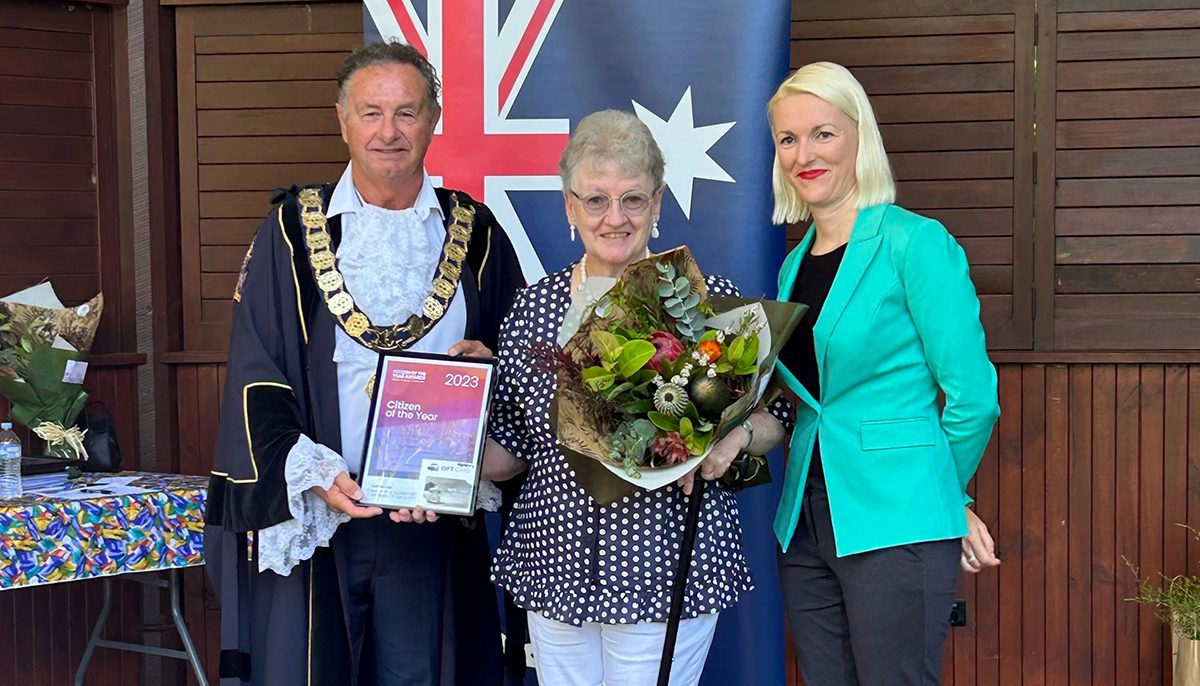 Three people standing in front of the Australian flag.