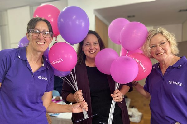 Three women with pink and purple balloons.