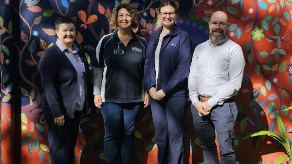 Four people standing in front of a colourful wall