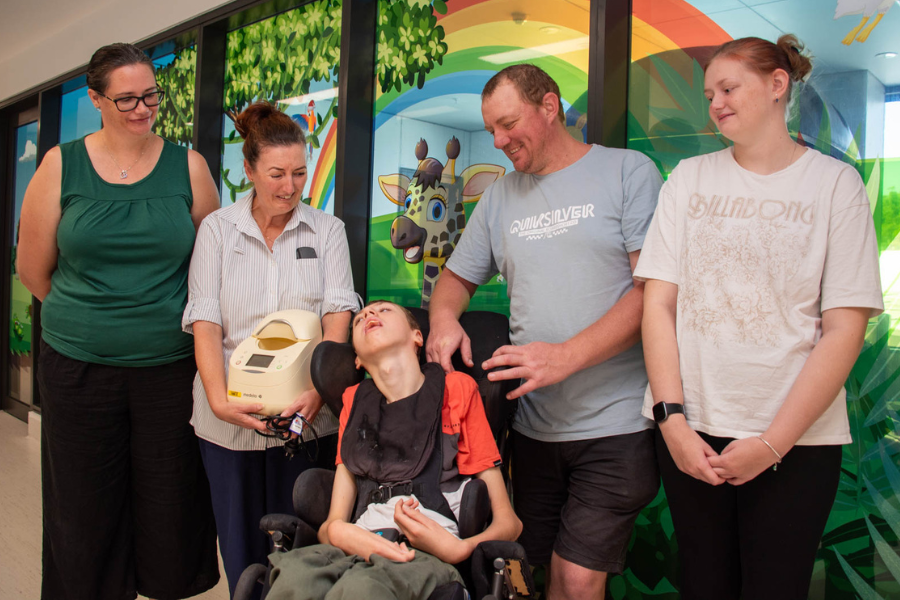 A family donating a milk warmer to a healthcare worker in a children's hospital ward.