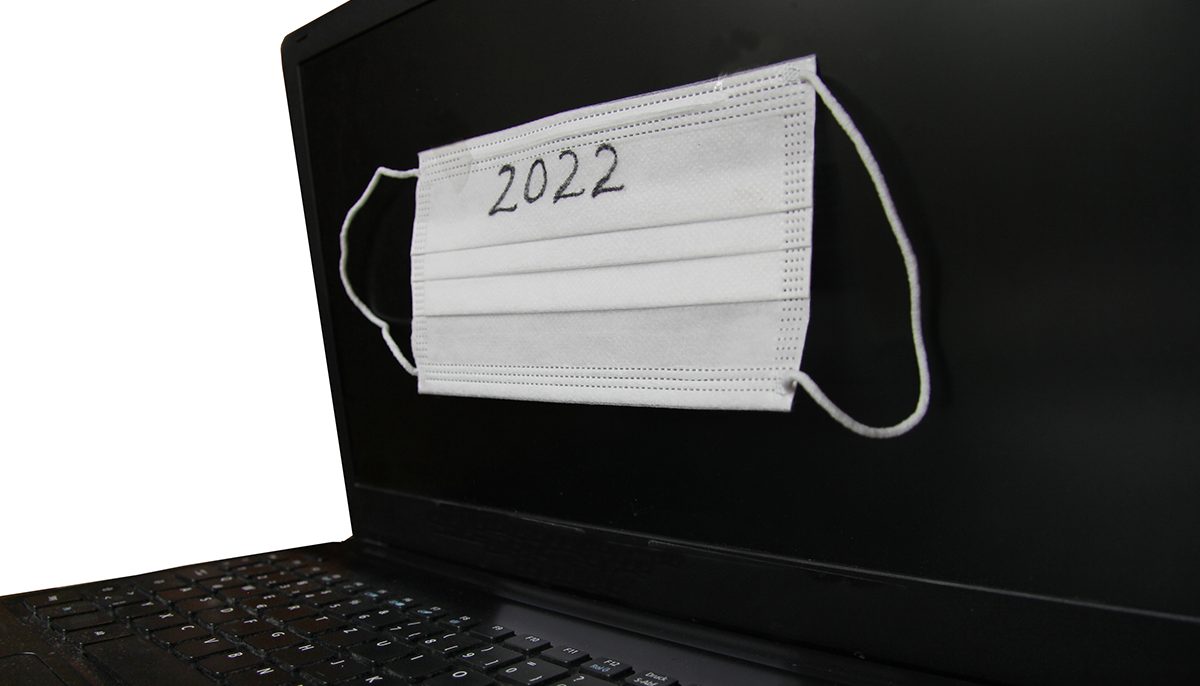 laptop with a mask on it. written on the mask is 2022