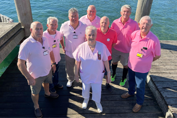 A group of men and one woman wearing pink shirts.