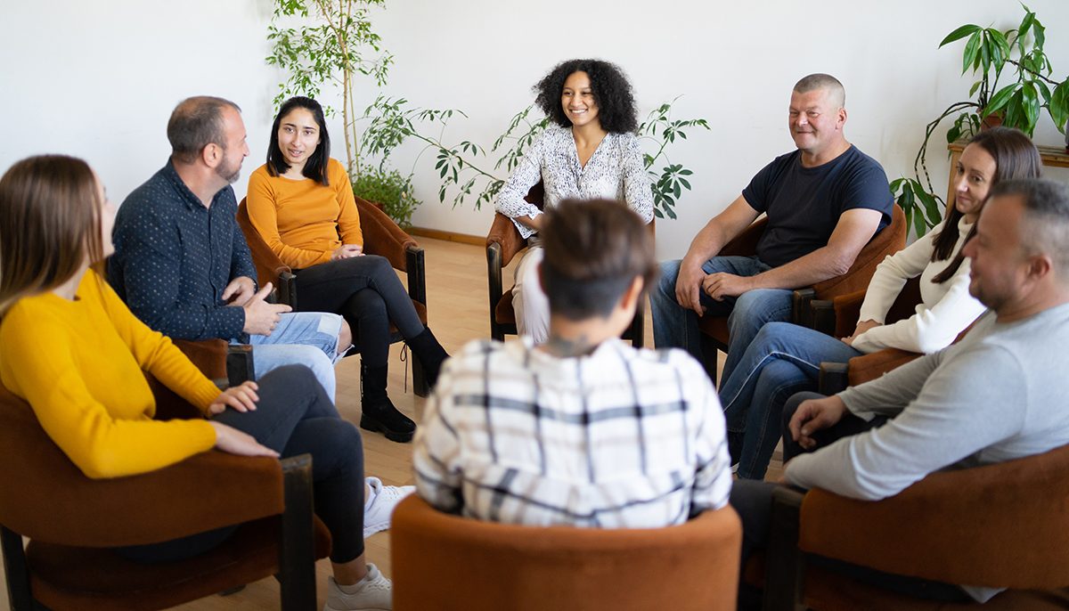 a group of people sitting in a circle have a discussion.