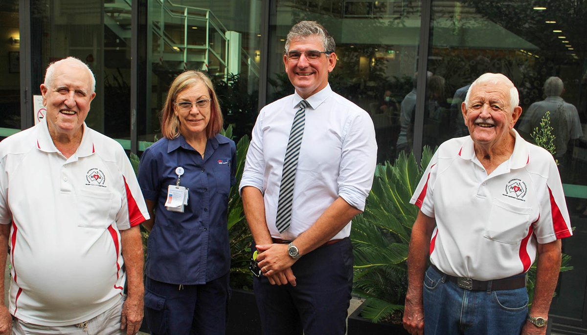 four people standing together, one a nurse and one a doctor. The other two older men are volunteers.