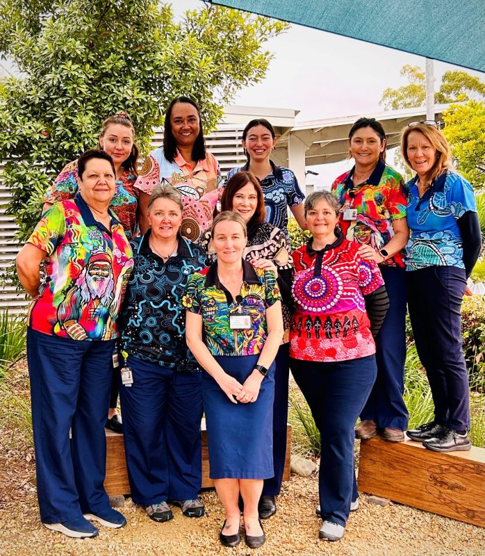 Ten women wearing colourful indigenous shirts.