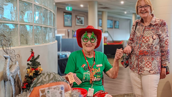 Two women smiling, one dressed in Christmas theme.
