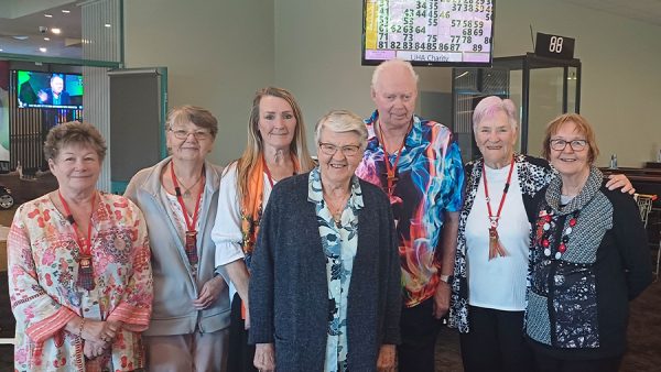 Seven older people standing together.