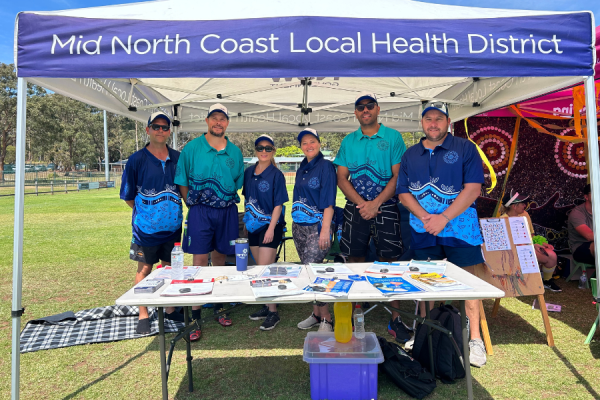 Mid North Coast Local Health District team at a community mental health event standing beneath a marquee