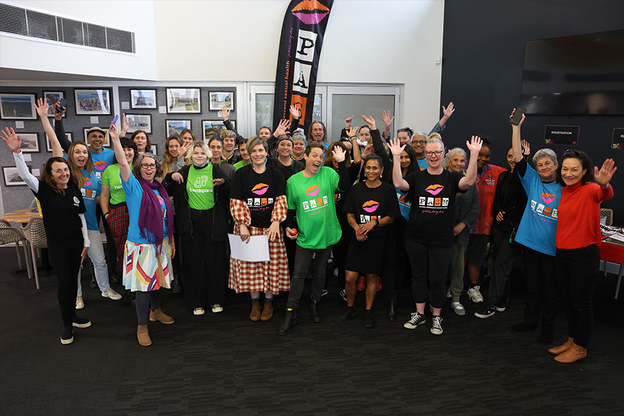 A group photo of people standing with the arms up in the air and smiling.