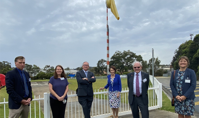 Group of people in front of helipad and wind sock