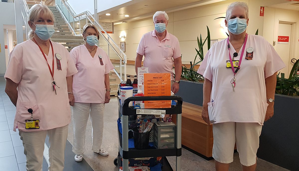 four people standing around a trolley loaded with personal care items and snacks.