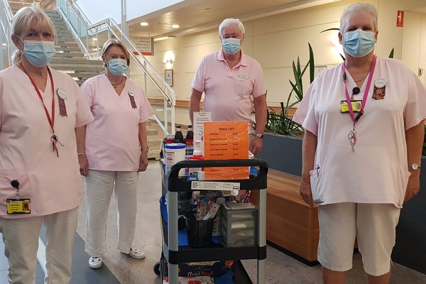 four people standing around a trolley loaded with personal care items and snacks.