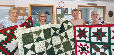 four women holding quilts
