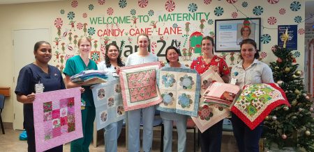 a group of midwives and doctors holding baby quilts. 