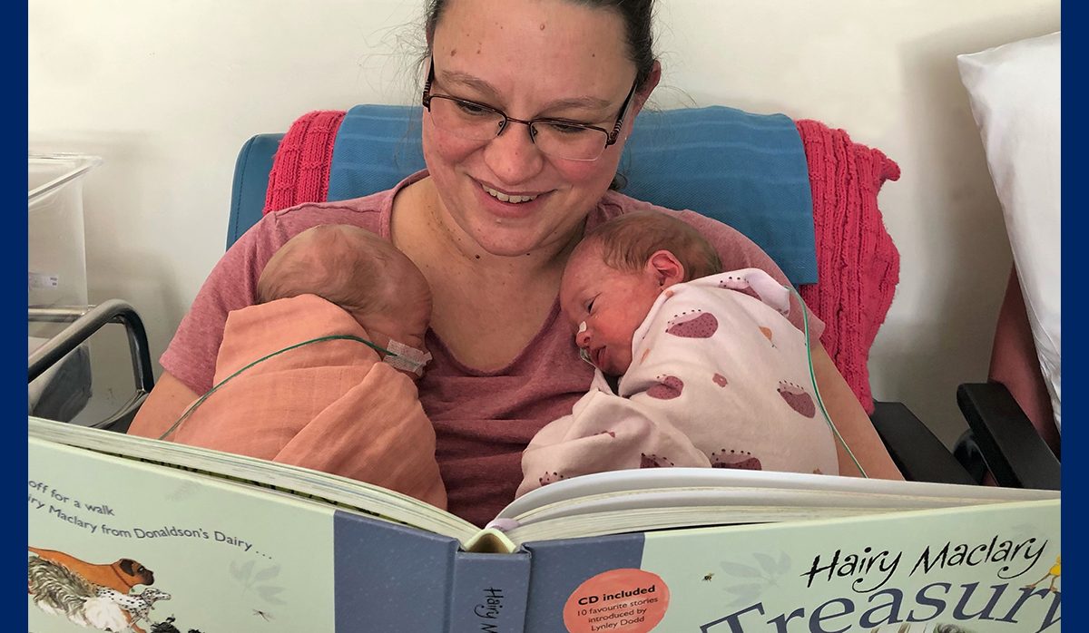 woman reading to new-born twins