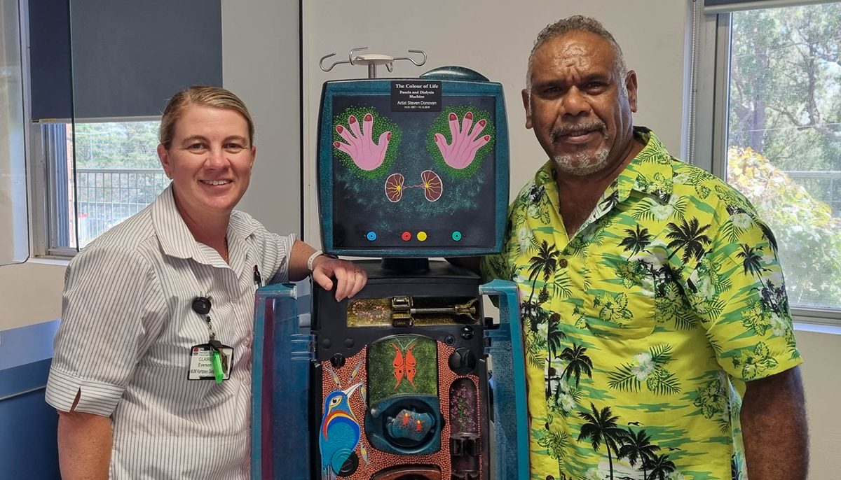 a nurse with an Aboriginal man standing either side of a dialysis machine.