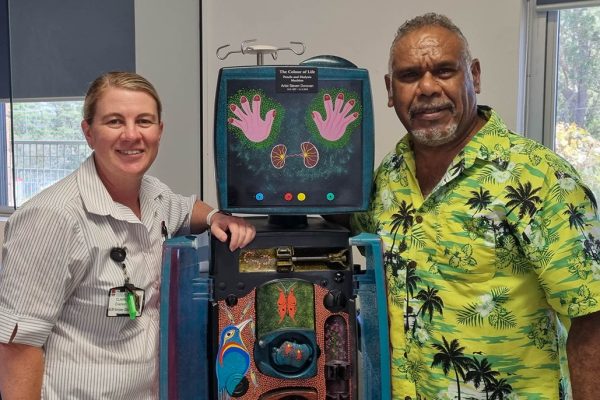 a nurse with an Aboriginal man standing either side of a dialysis machine.