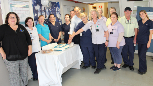 Hospital staff smiling and cutting a cake.