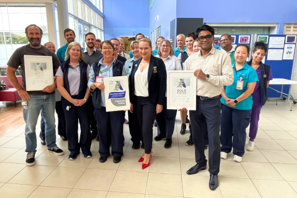 A group of people in medical uniforms standing in a hospital holding certificates.