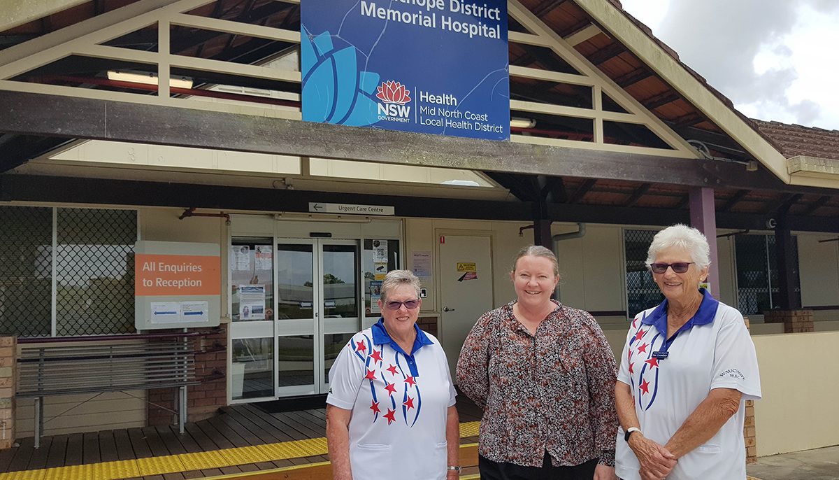 three women standing in front of a hospital