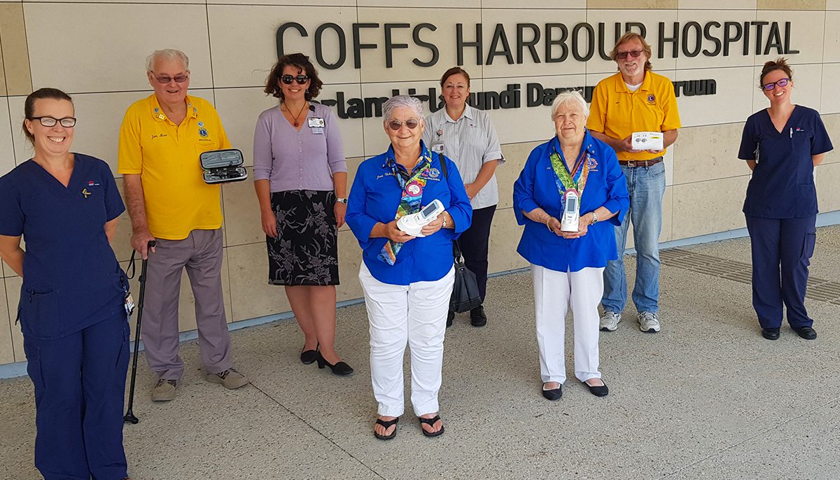 a group of volunteers holding small pieces of equipment in the company of midwives outside Coffs Harbour Hospital