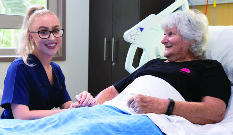 Nurse holding a patient's hand smiling