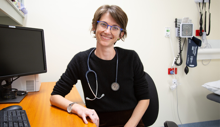 Doctor sitting in a clinic room smiling.