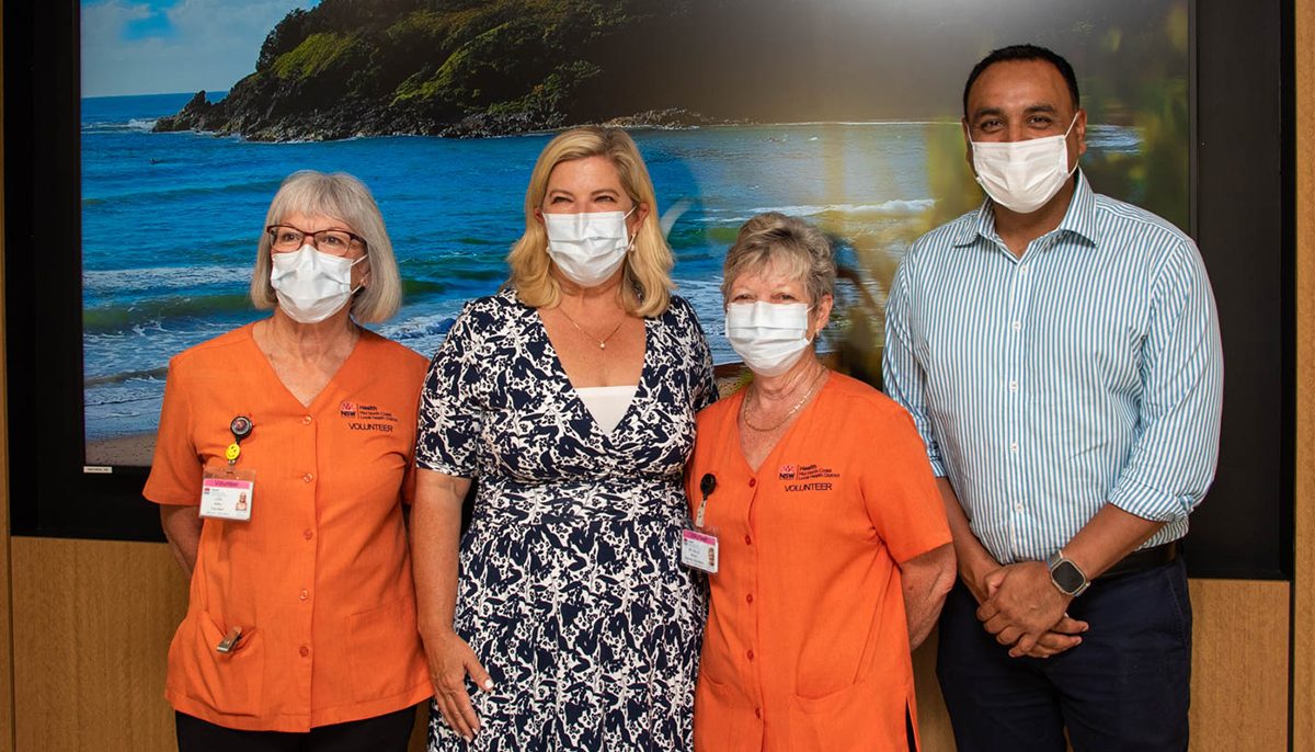 Two women wearing orange shirts standing with two MPs - one female and one male.