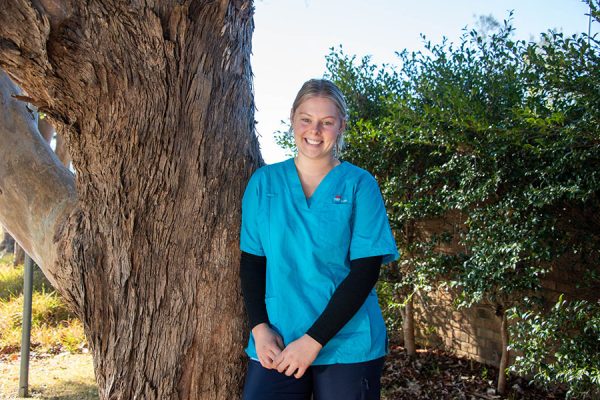 occupational therapist leaning against a tree