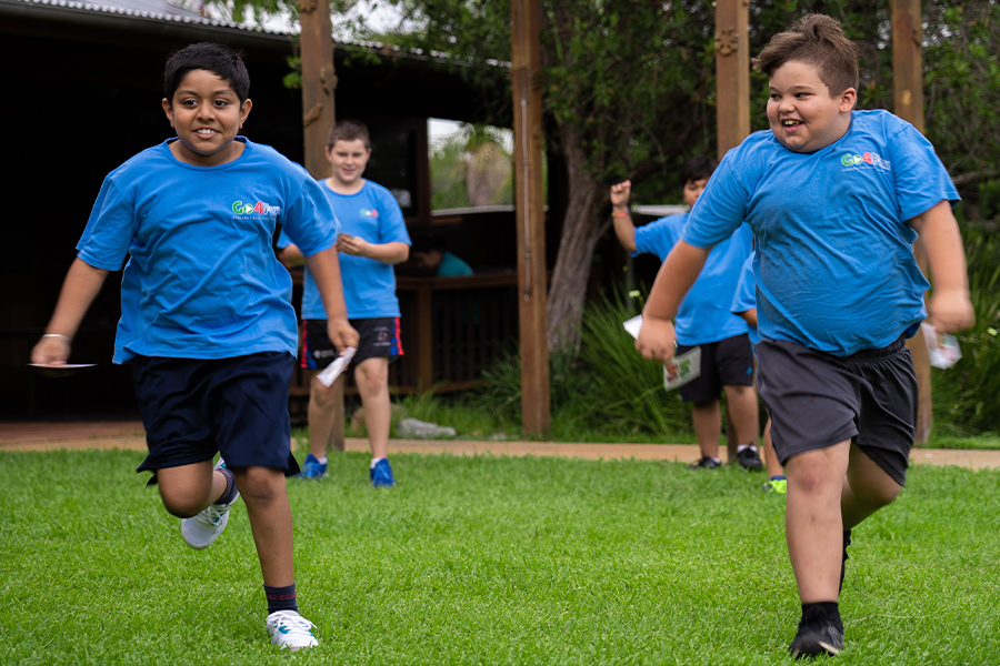 Two young boys running side by side and smiling