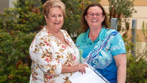 Two healthcare workers, one holding a certificate of service recognition.
