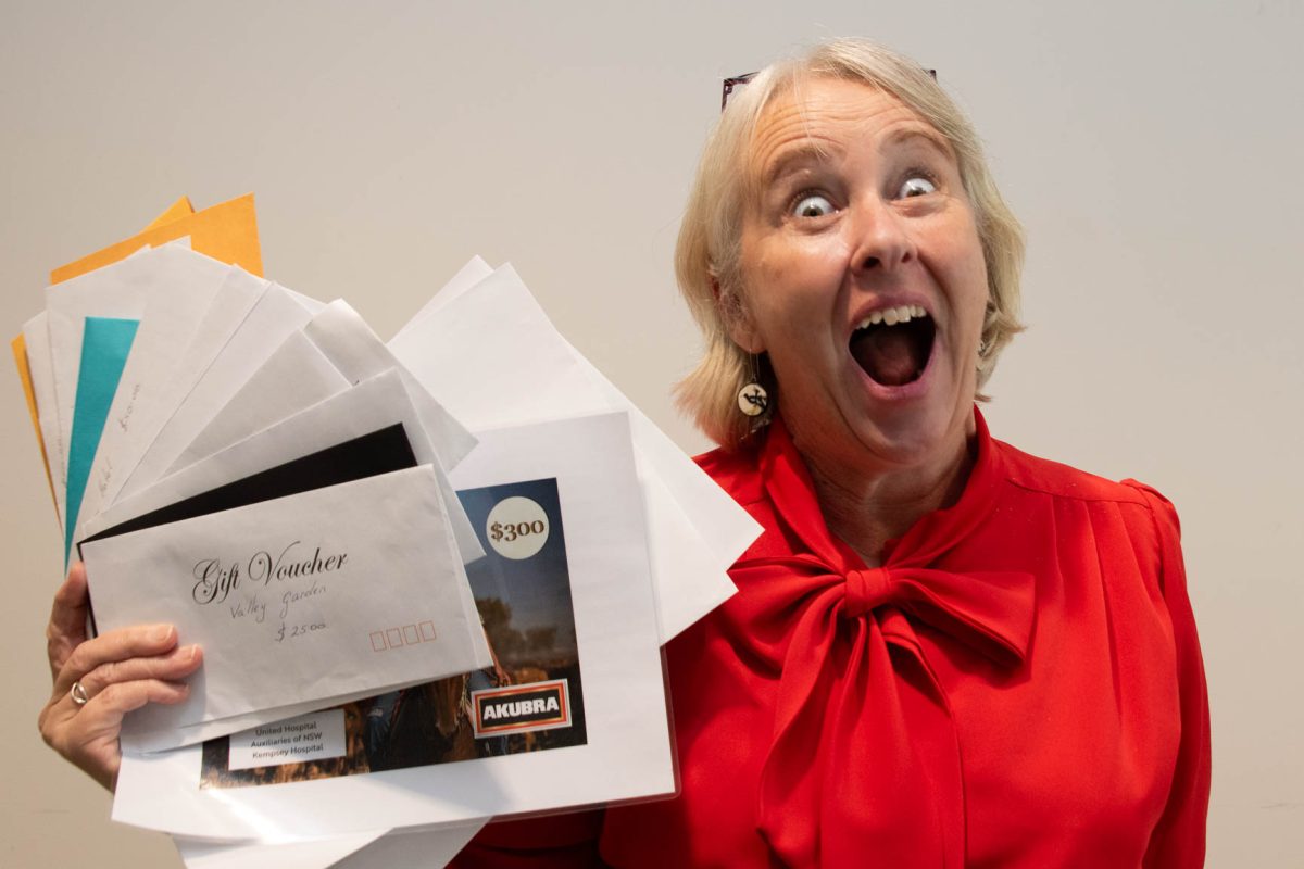 A lady wearing a red shirt holding up a pieces of paper